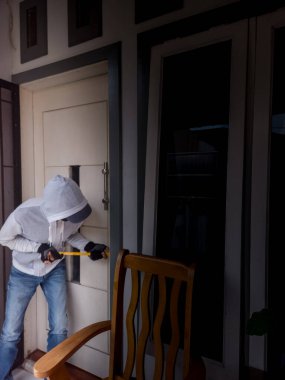 Bir hırsızın levye kullanarak evin kapısını açtığı görüntüsü.