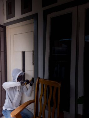 Bir hırsızın levye kullanarak evin kapısını açtığı görüntüsü.