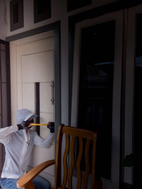 Bir hırsızın levye kullanarak evin kapısını açtığı görüntüsü.