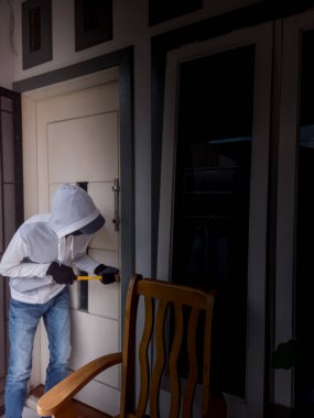 Bir hırsızın levye kullanarak evin kapısını açtığı görüntüsü.