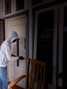 Bir hırsızın levye kullanarak evin kapısını açtığı görüntüsü.