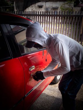 Bir hırsızın evde park etmiş bir arabanın kapısını açtığı görüntüsü.