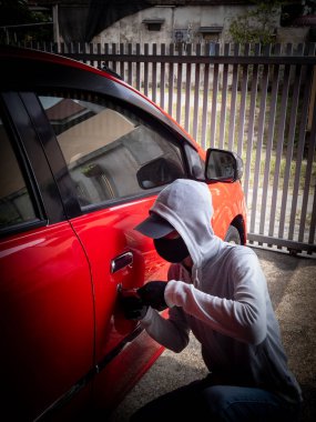 Bir hırsızın evde park etmiş bir arabanın kapısını açtığı görüntüsü.