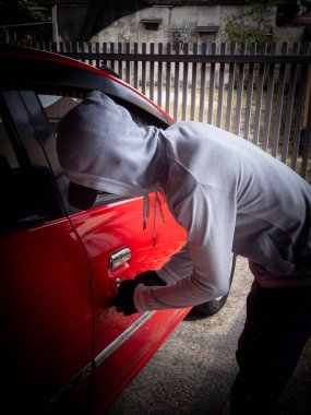 Bir hırsızın evde park etmiş bir arabanın kapısını açtığı görüntüsü.