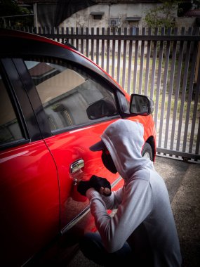Bir hırsızın evde park etmiş bir arabanın kapısını açtığı görüntüsü.