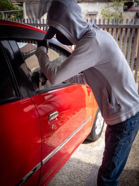 Bir hırsızın evde park etmiş bir arabanın kapısını açtığı görüntüsü.