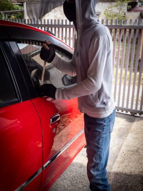 Bir hırsızın evde park etmiş bir arabanın kapısını açtığı görüntüsü.