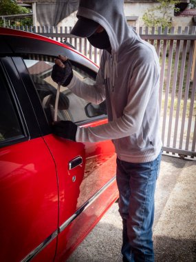 Bir hırsızın evde park etmiş bir arabanın kapısını açtığı görüntüsü.