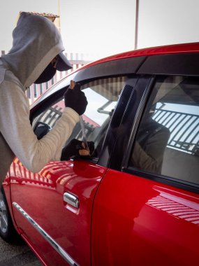 Bir hırsızın evde park etmiş bir arabanın kapısını açtığı görüntüsü.