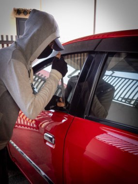 Bir hırsızın evde park etmiş bir arabanın kapısını açtığı görüntüsü.