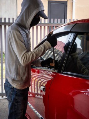 Bir hırsızın evde park etmiş bir arabanın kapısını açtığı görüntüsü.