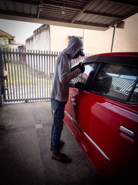 Bir hırsızın evde park etmiş bir arabanın kapısını açtığı görüntüsü.