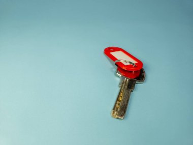 Açık mavi arkaplanda izole edilmiş anahtarlıklı kapı anahtarı