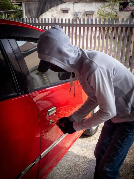 Bir hırsızın evde park etmiş bir arabanın kapısını açtığı görüntüsü.