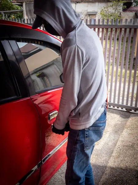 Bir hırsızın evde park etmiş bir arabanın kapısını açtığı görüntüsü.