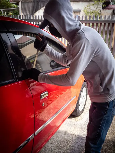 Bir hırsızın evde park etmiş bir arabanın kapısını açtığı görüntüsü.