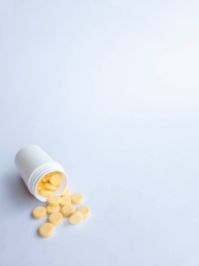 B vitamini hapları ve beyaz arka planda beyaz bir takviye şişesi.