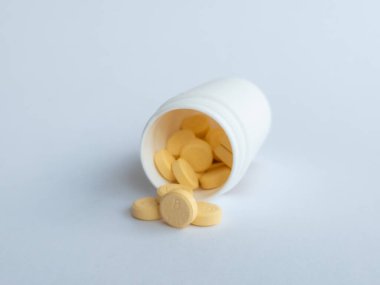 B vitamini hapları ve beyaz arka planda beyaz bir takviye şişesi.