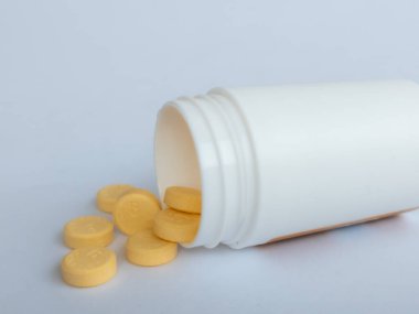 B vitamini hapları ve beyaz arka planda beyaz bir takviye şişesi.