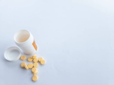 B vitamini hapları ve beyaz arka planda beyaz bir takviye şişesi.