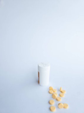 B vitamini hapları ve beyaz arka planda beyaz bir takviye şişesi.