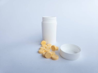 B vitamini hapları ve beyaz arka planda beyaz bir takviye şişesi.