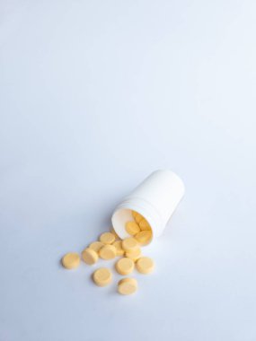 B vitamini hapları ve beyaz arka planda beyaz bir takviye şişesi.