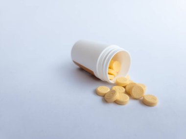 B vitamini hapları ve beyaz arka planda beyaz bir takviye şişesi.