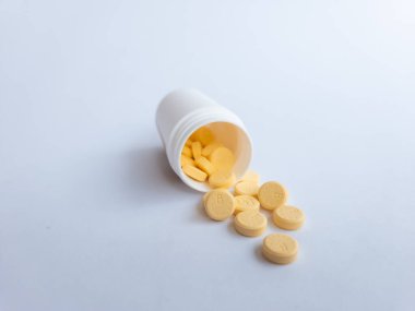 B vitamini hapları ve beyaz arka planda beyaz bir takviye şişesi.