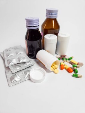 İlaçlar, tabletler, kapsüller ve sıvı ilaç şişeleri de dahil olmak üzere çeşitli ilaçlar temiz beyaz bir arkaplanda düzenlenmiştir. Olay yeri sağlık, tedavi veya ilaç ürünleri öneriyor.