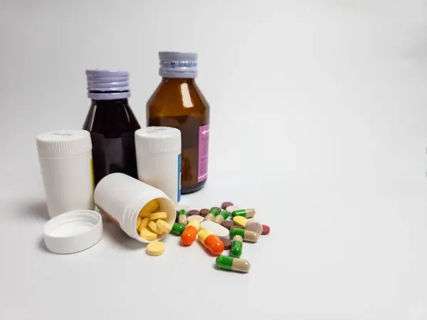 İlaçlar, tabletler ve kapsüller de dahil olmak üzere çeşitli ilaçlar temiz beyaz bir yüzeyde ilaç şişelerinin yanında düzenlenir. Sağlık ve İlaç Hizmetleri Konsepti.