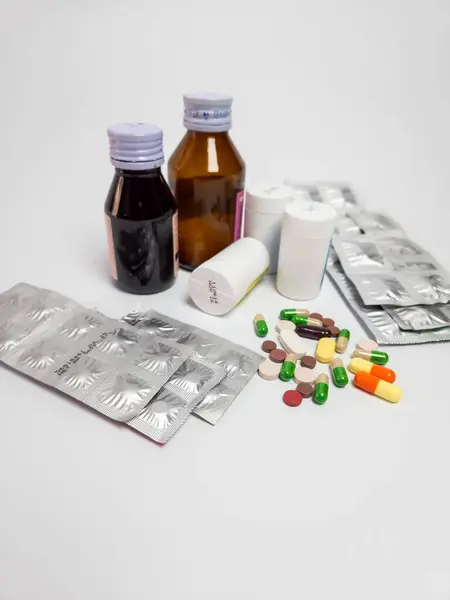 Bu resimde, temiz beyaz bir arkaplanda düzenlenmiş tabletler, haplar ve şurup şişeleri de dahil olmak üzere çeşitli ilaçlar yer alıyor. Sağlık hizmetleri kavramlarının, ilaç ürünlerinin ve tıbbi tedavilerin resmedilmesi için ideal.