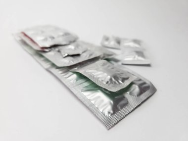 Kapalı gümüş folyo ambalajlı bir prezervatif yığınının beyaz arka planda yakın plan görüntüsü. Güvenli seks, doğum kontrolü ve cinsel sağlık kavramı. Cinsel yolla bulaşan enfeksiyonlara karşı koruma.