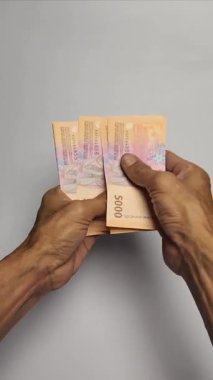 Bir adam 5,000 rupiah banknot sayıyor..
