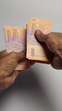 Bir adam 5,000 rupiah banknot sayıyor..