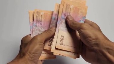 Bir adam 5,000 rupiah banknot sayıyor..