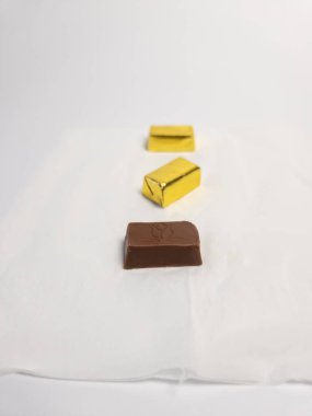 Arkaplanda altın sarısı şekerler ile paketlenmemiş çikolata şekeri