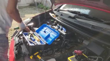 Bir tamirci evde kendi arabasını tamir ediyor.
