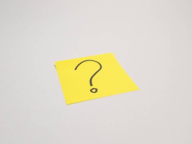 Üzerinde el çizimi siyah soru işareti olan parlak sarı yapışkan bir not düz beyaz bir arkaplan üzerine kuruludur. Görüntü belirsizliği, sorgulamayı ya da cevap ihtiyacını iletir. Sahnenin basitliği onu çeşitli kullanımlar için kullanışlı kılıyor..
