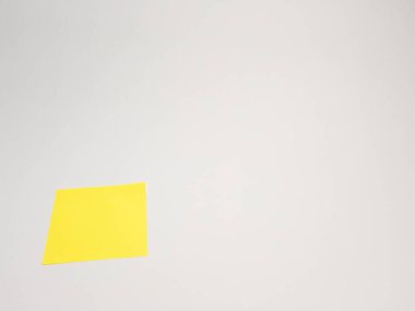 Temiz beyaz bir yüzeye yerleştirilmiş tek bir sarı yapışkan nota yakın çekim. Resim, hatırlatıcılar, notlar veya iletiler ile ilgili kavramların iletilmesi için idealdir. Ofis ortamlarından kişisel organizasyonlara kadar çeşitli bağlamlarda kullanmak için uygundur.