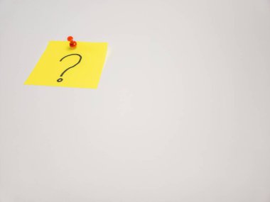 Yakın plan çekimde üzerinde siyah soru işareti olan sarı bir post-it bulunur. Not kırmızı bir raptiyeyle düz beyaz bir yüzeye tutturulmuş. Kompozisyon, sarı nota ile beyaz arkaplan arasındaki karşıtlığa odaklanır.