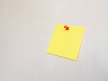 Kırmızı raptiyeli beyaz bir yüzeye iliştirilmiş parlak sarı yapışkan bir notanın yakın plan çekimi. Not boş, mesaj ya da metin için kopyalama alanı sunuyor. Görüntü iyi aydınlatılmış ve temiz bir kompozisyon içeriyor, çeşitli tasarım ve kombinasyonlar için mükemmel.