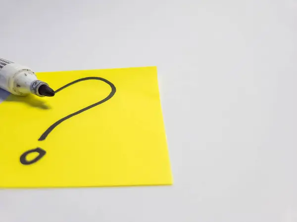 Üzerinde beyaz bir yüzey üzerinde siyah bir kalemle el çizimi bir soru işareti bulunan parlak sarı yapışkan bir not. Sorgulamayı, belirsizliği ve problem çözmeyi sembolize eder. Basit ve temiz kompozisyon.