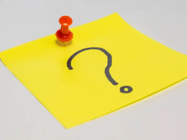 Üzerinde siyah soru işareti olan sarı yapışkan bir nota yakın çekim, kırmızı bir raptiyeyle beyaz bir yüzeye tutturulmuş. Görüntü belirsizliği, soruları ve cevap ihtiyacını iletir. Eğitim, iş ve yaratıcı projeler için ideal.