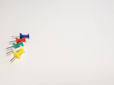 Beyaz bir yüzeyde çapraz dizilmiş renkli raptiye koleksiyonu. Resim, mavi, kırmızı, yeşil ve sarı olmak üzere beş adet iğne içermektedir. Bu resim ofis malzemeleri, organizasyon ve proje yönetimi ile ilgili kavramları göstermek için uygundur