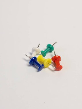 Temiz beyaz bir yüzeye yerleştirilmiş, canlı renklerini gösteren beş renkli iğneden oluşan yakın plan bir çekim. İğneler, renkli başlarla gümüş iğneler arasındaki zıtlığı vurgulayan görsel açıdan cazip bir düzende konumlandırılmış. Th
