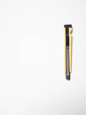 Yakın plan bir stüdyoda beyaz arka planda sarı bir bıçak sergilenir. Bıçak dikey olarak, siyah bir sürgülü mekanizma ve keskin bir bıçakla yerleştirilmiş. Görüntü iyi aydınlatılmış, aracın detaylarını vurguluyor ve temiz, minimalist