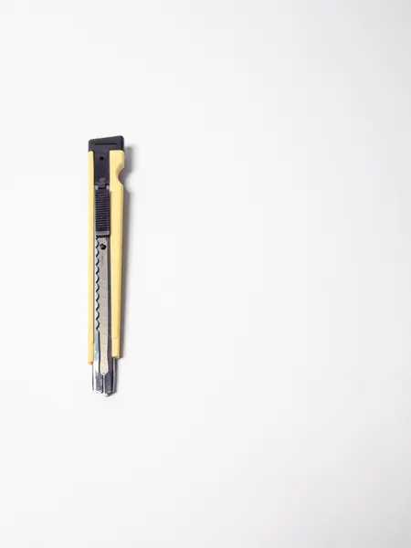 Bu stüdyo çekiminde sarı bir maket bıçağı yer alır, aynı zamanda kullanım bıçağı olarak da bilinir, düz beyaz bir arka planda. Görüntü iyi aydınlatılmış, aracın detaylarını vurguluyor. Odaklanma keskindir ve kompozisyon basittir, çeşitlilik için uygundur.