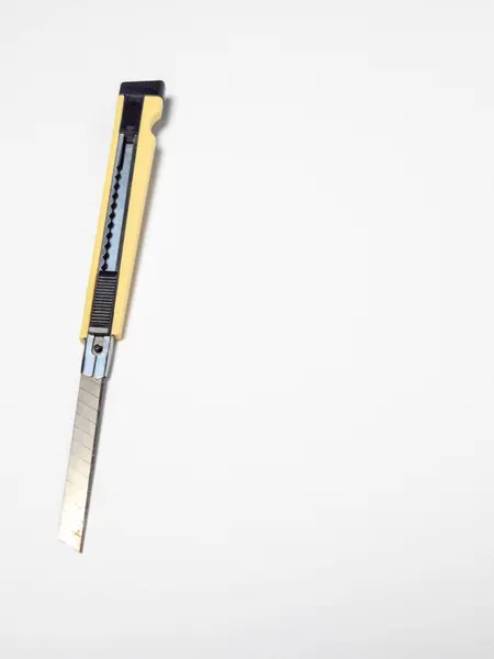 Sarı saplı, temiz beyaz bir arka planda izole edilmiş bir bıçakla yakın çekim. Keskin kenarı ve metalik yapıyı gösteren bıçak genişletilmiş. Görüntü iyi aydınlatılmış, bıçağın detaylarına odaklanmış. İdeal.