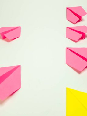 Pembe ve sarı kağıt uçaklar içeren canlı bir görüntü. Temiz, beyaz bir arkaplan üzerine yerleştirilmiş. Parlak renkleri ve geometrik şekilleri vurgulayarak kompozisyon basit ama görsel olarak çekici. Uçaklar stratejik olarak...